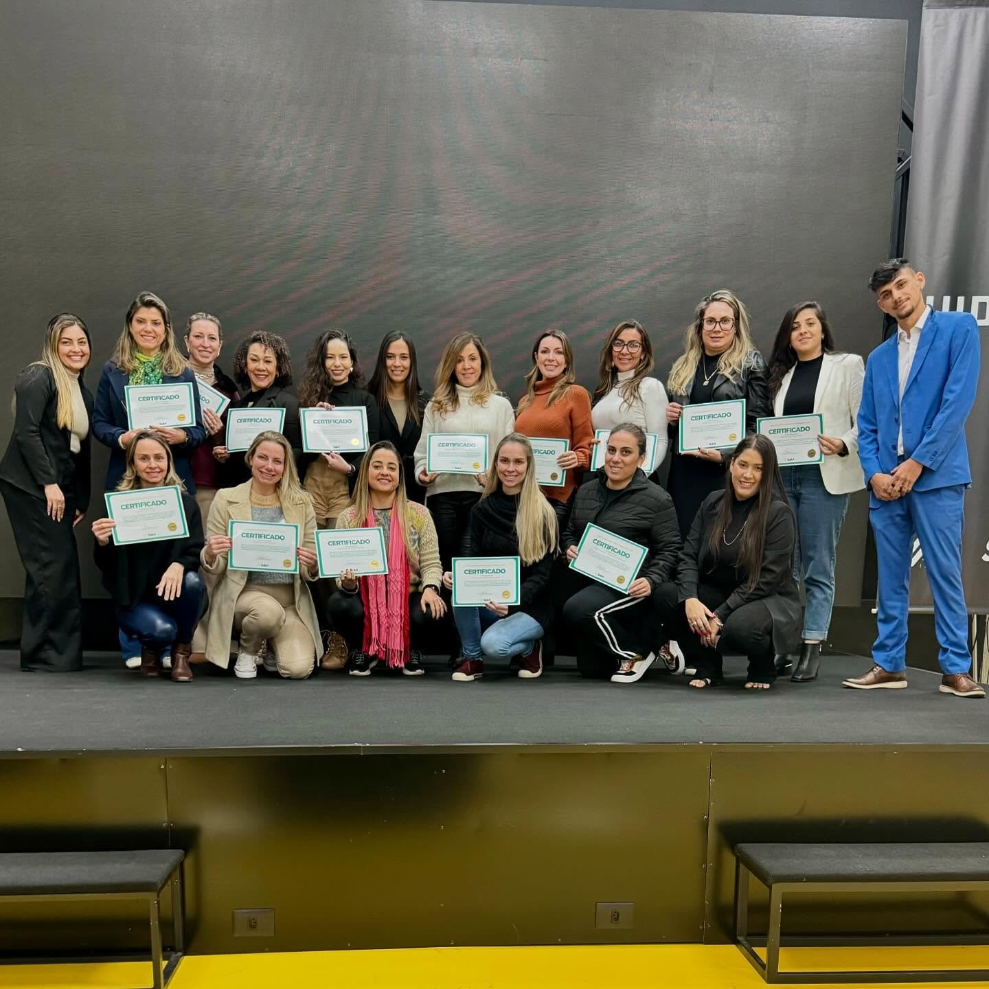 Formandos no palco de evento da Salut segurando certificados